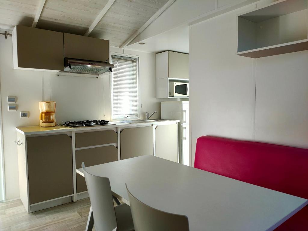une cuisine avec une table blanche et une chaise rouge dans l'établissement Camping les Oliviers, à Oraison 12 autres photos
