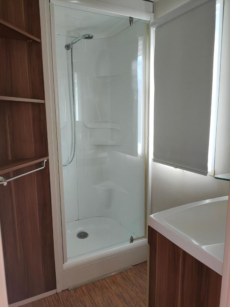 une douche avec une porte vitrée dans une salle de bain dans l'établissement Camping les Oliviers, à Oraison
