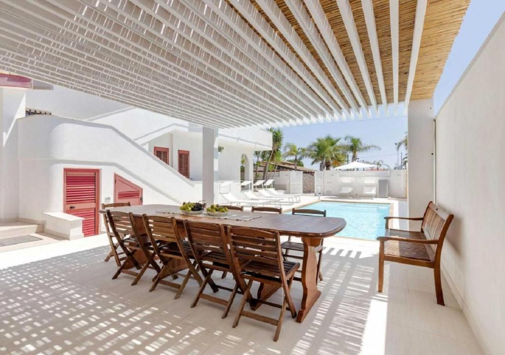 - une table et des chaises sur une terrasse avec piscine dans l'établissement Villa Rosimeli, à Ispica