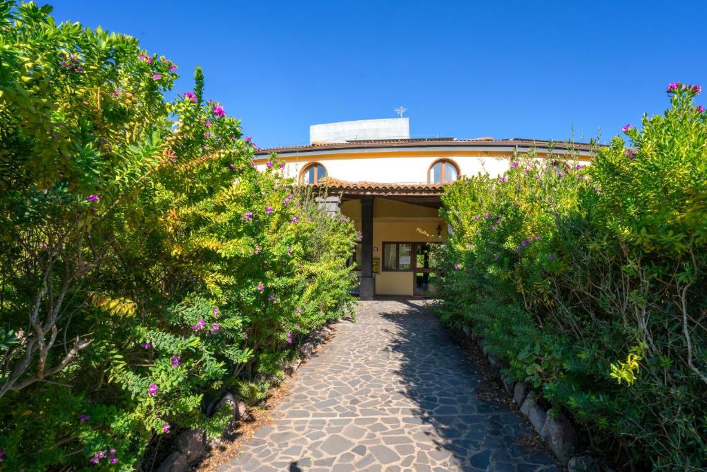 un chemin de jardin menant à une maison entourée de buissons dans l'établissement Hotel surrounded by greenery with swimming pool in Arborea just 600 meters from the sea, à Arborea