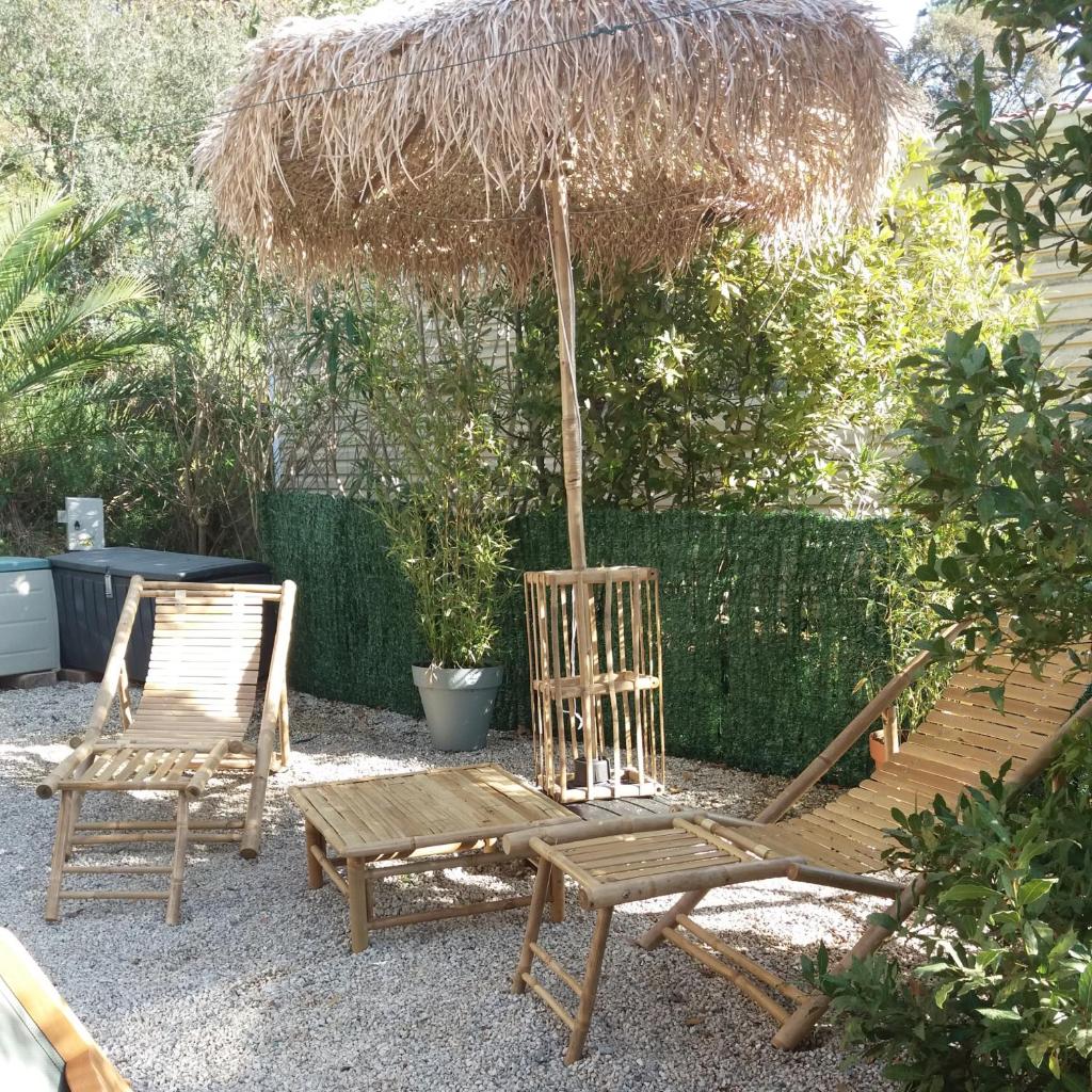 2 chaises en bois, un parasol et un banc dans l'établissement SAS CAMPING PARC MONTANA, à Gassin
