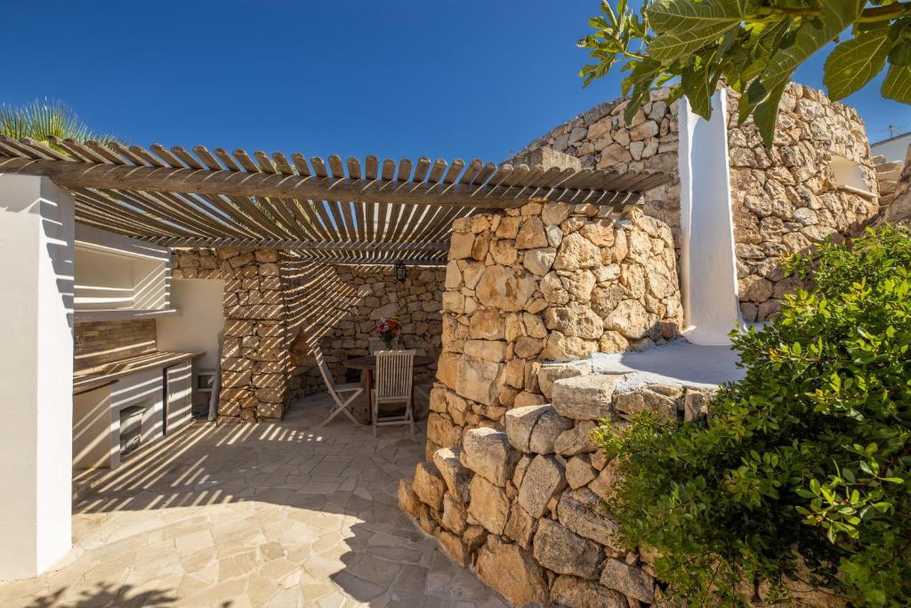 une terrasse avec un mur en pierre et une pergola en bois. dans l'établissement Tenuta Zahir, à Marina di Mancaversa