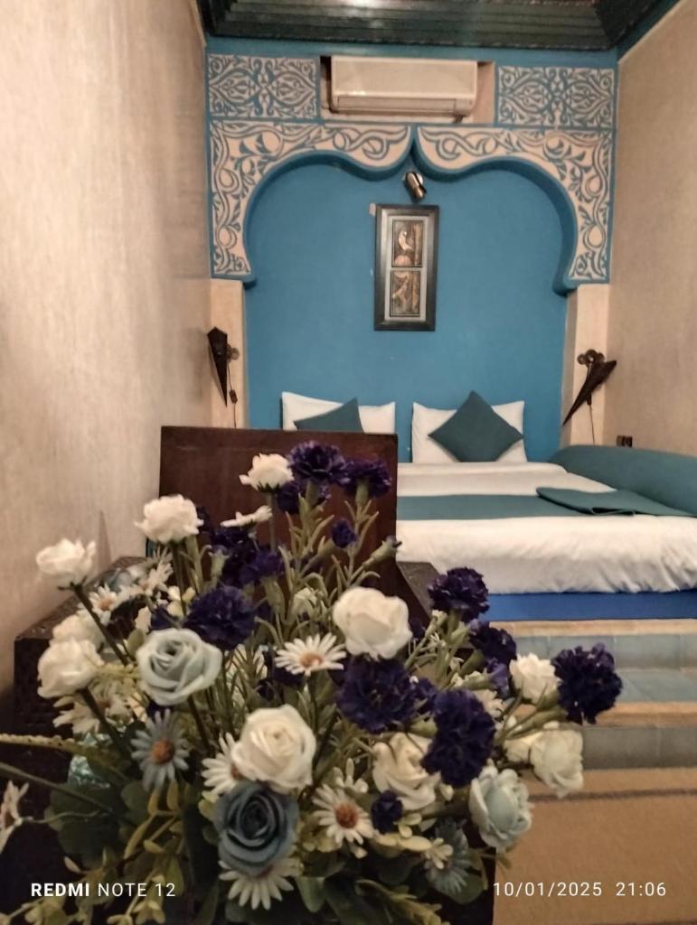 - une chambre bleue avec un lit et un bouquet de fleurs dans l'établissement Riad Mille Et Une Nuits, à Marrakech