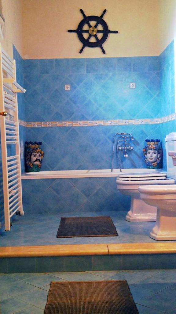 La salle de bains est pourvue d'un lavabo et d'une baignoire avec une roue sur le mur. dans l'établissement Casa il Faro villa con piscina, à Castelmola