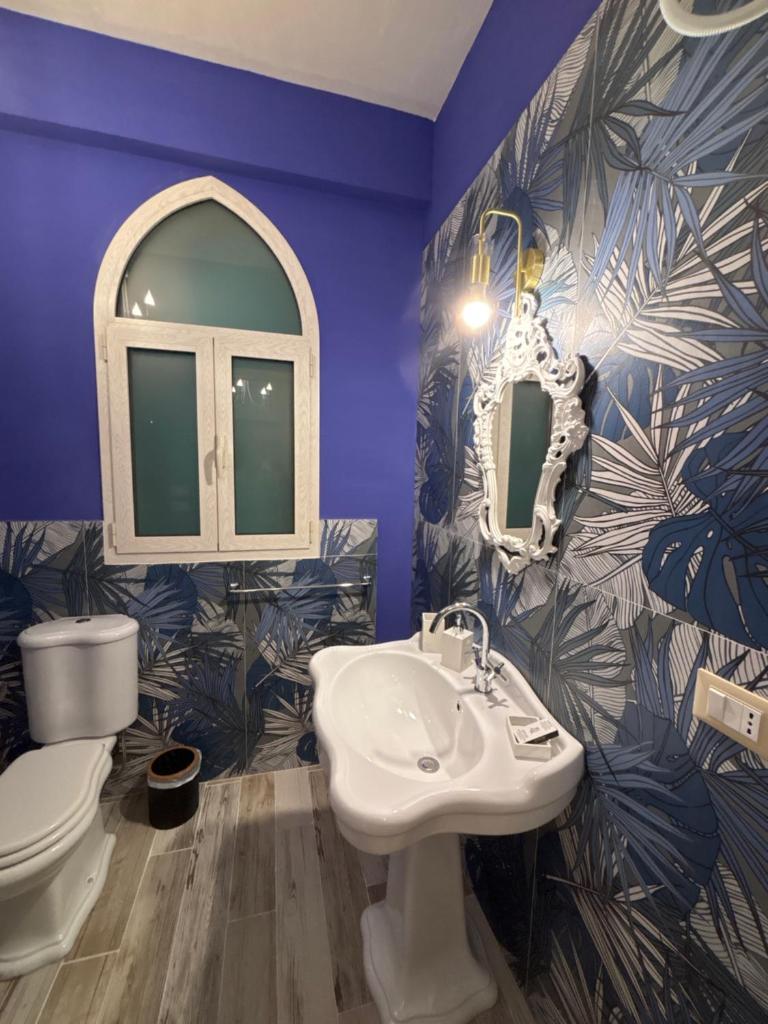 une salle de bains pourpre avec un lavabo et des toilettes. dans l'établissement Villa Brikinnia, à Lentini