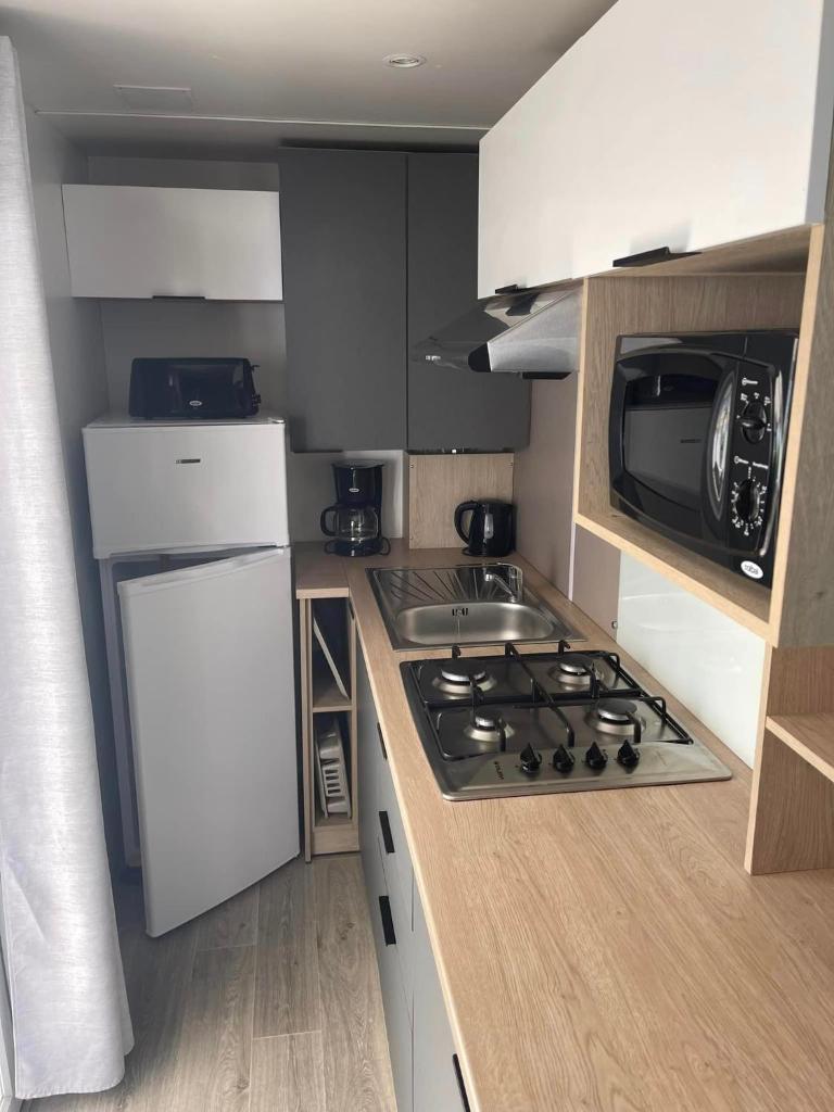 une petite cuisine avec une cuisinière et un micro-ondes dans l'établissement Mobil-home premium 325, à Narbonne