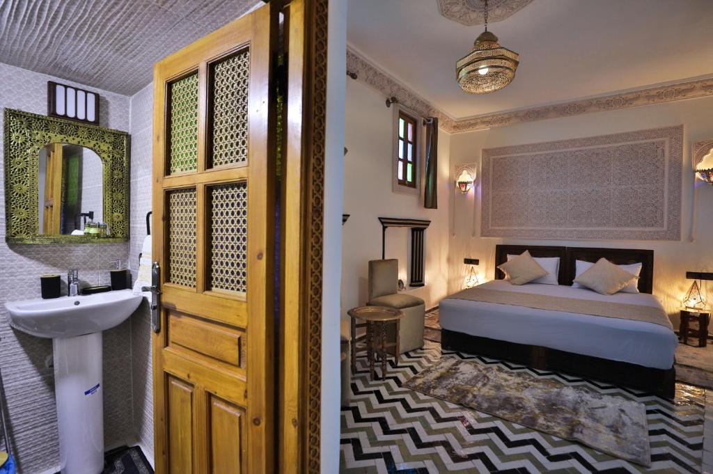 une chambre avec un lit, un lavabo et un miroir dans l'établissement Dar derb el miter, à Fès