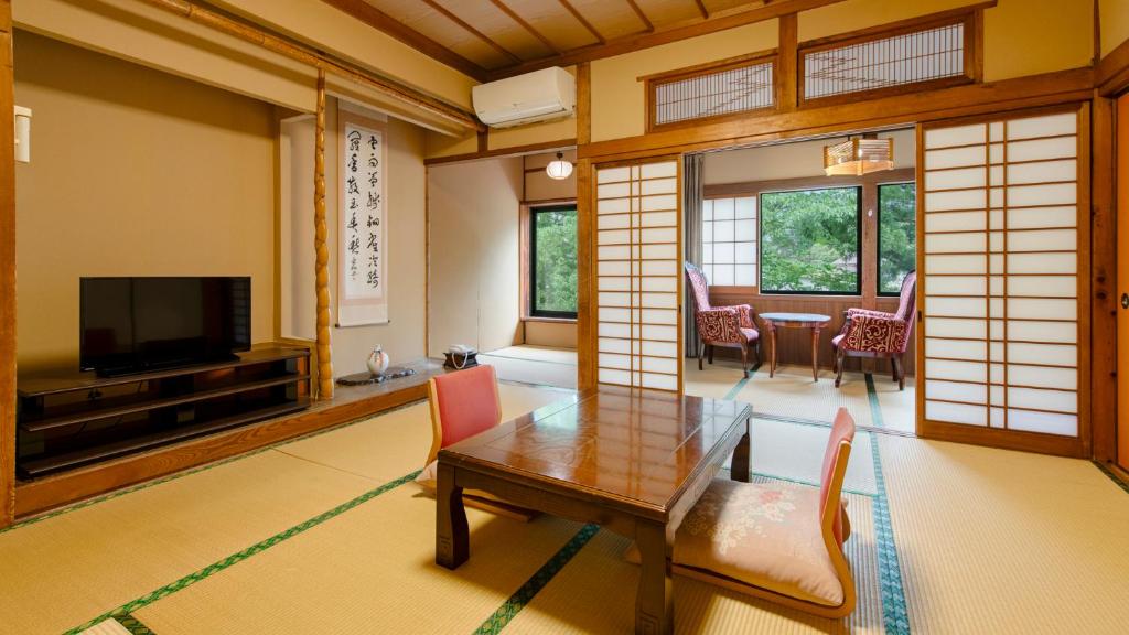 un salon avec une table et une télévision dans l'établissement Unzen Iwaki Ryokan, à Unzen