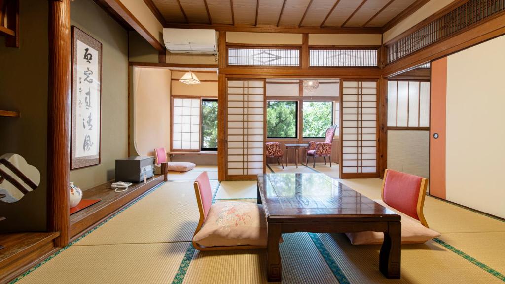 un salon avec une table et des chaises en bois dans l'établissement Unzen Iwaki Ryokan, à Unzen