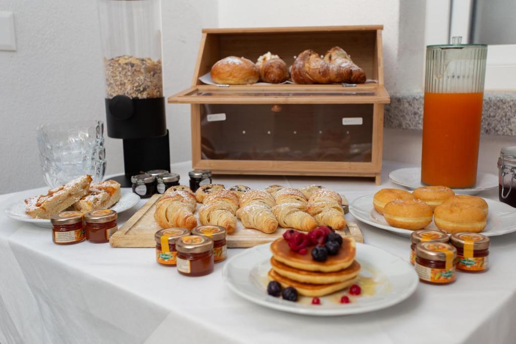 une table avec des assiettes de nourriture et des pâtisseries dessus dans l'établissement Alexander House Hotel, à San Ferdinando