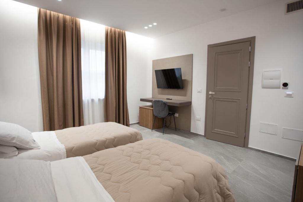 une chambre d'hôtel avec deux lits et une télévision dans l'établissement Alexander House Hotel, à San Ferdinando