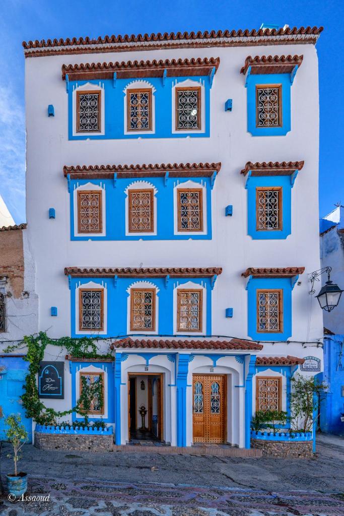 un bâtiment bleu et blanc avec des fenêtres dorées dans l'établissement Dar Kisania, à Chefchaouen