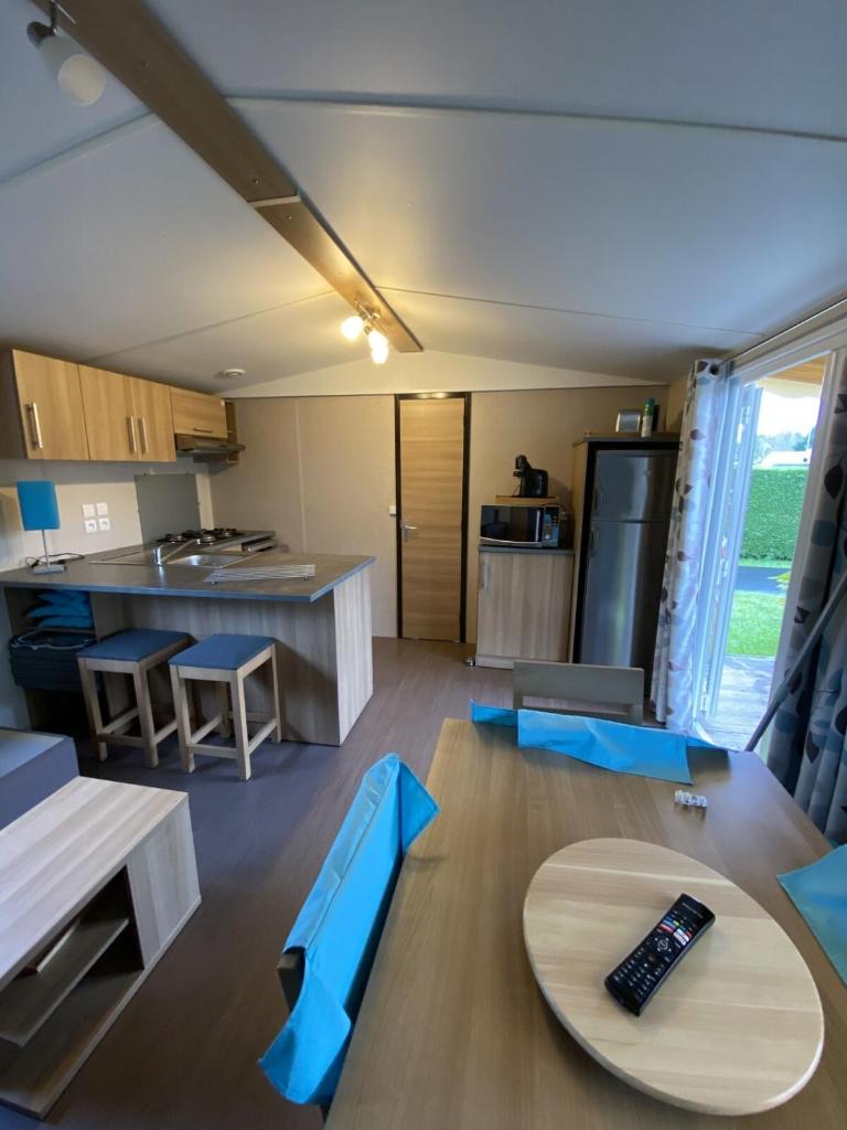 une cuisine et un salon avec des chaises bleues et une table dans l'établissement MobilHome Camping Deauville, à Saint-Arnoult