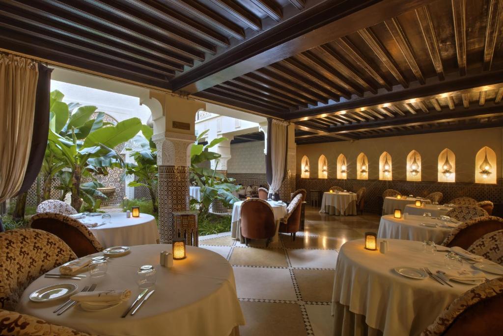un restaurant avec des tables et des chaises blanches et un chercheur de table dans l'établissement Riad Kheirredine, à Marrakech