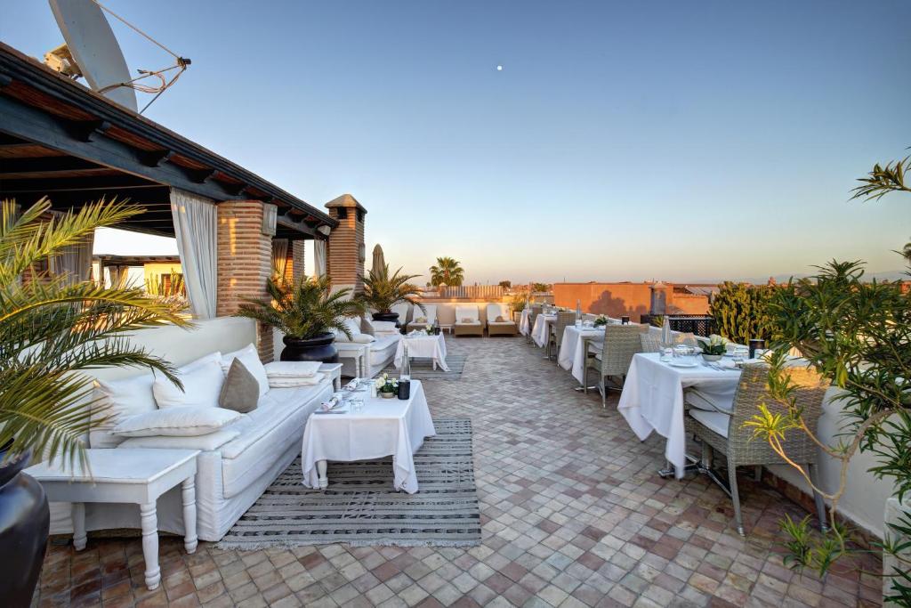 un restaurant avec des canapés blancs et des tables sur une terrasse dans l'établissement Riad Kheirredine, à Marrakech