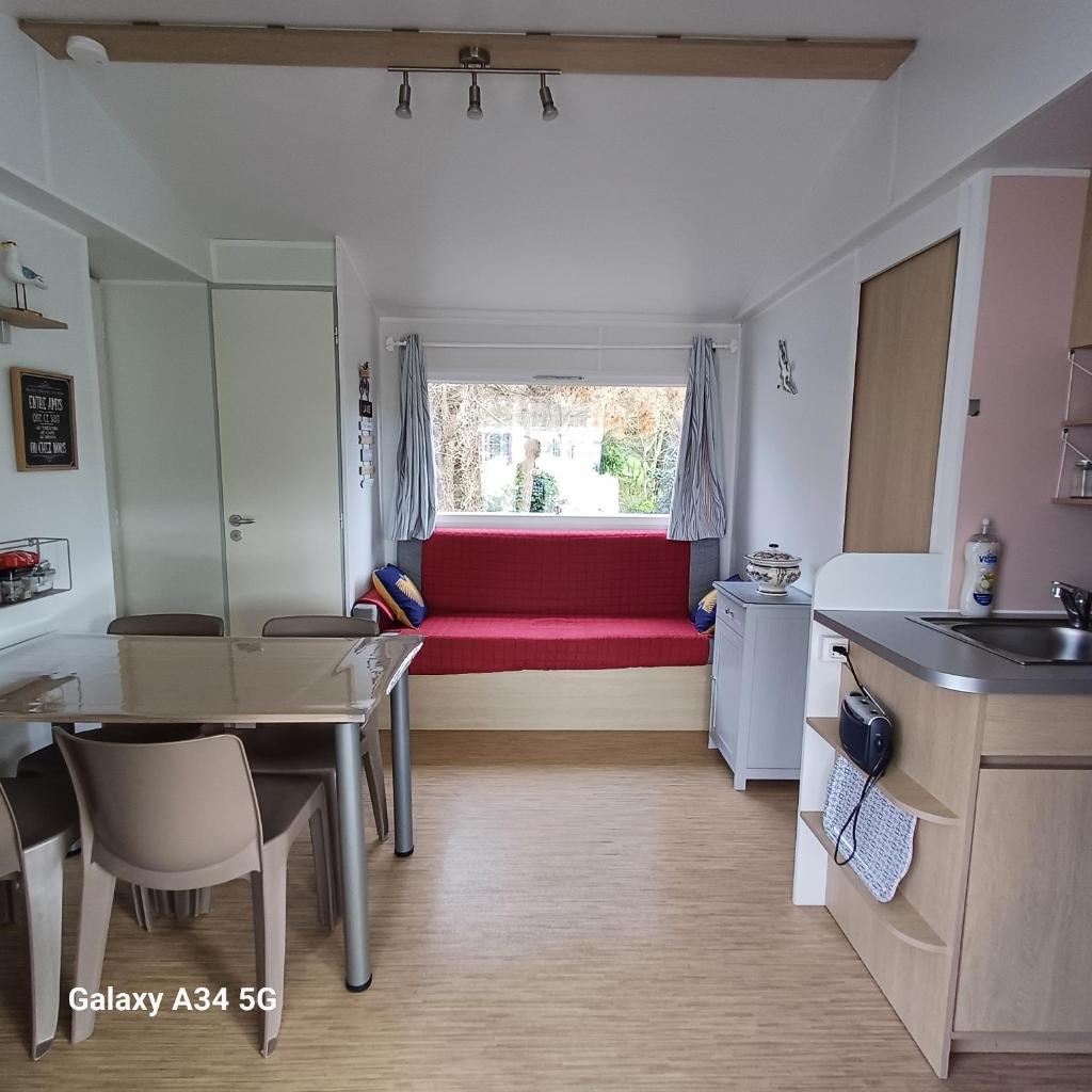 - un salon avec un canapé rouge et une fenêtre dans l'établissement Mobilhome camping Ernest Renan Louannec, à Louannec