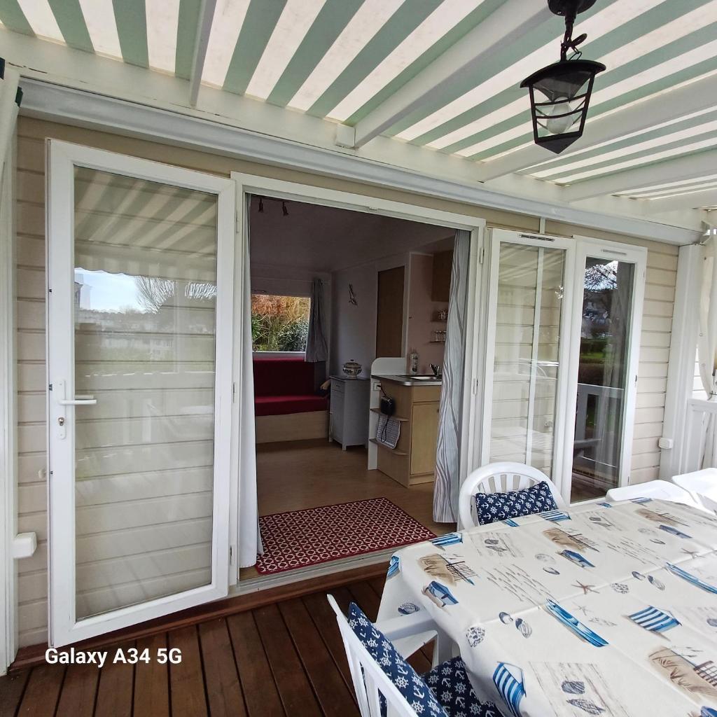 une porte coulissante en verre sur un patio avec une table dans l'établissement Mobilhome camping Ernest Renan Louannec, à Louannec