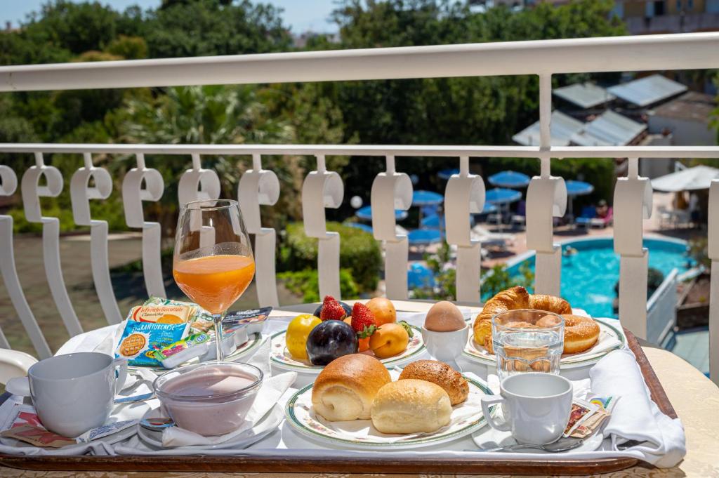 une table avec de la nourriture et des boissons pour le petit-déjeuner et une piscine dans l'établissement Hotel Regina Palace Terme, à Ischia