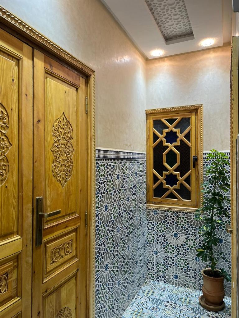 La salle de bains est pourvue d'une porte en bois et d'un mur en carrelage. dans l'établissement Riad dar lakbira, à Marrakech