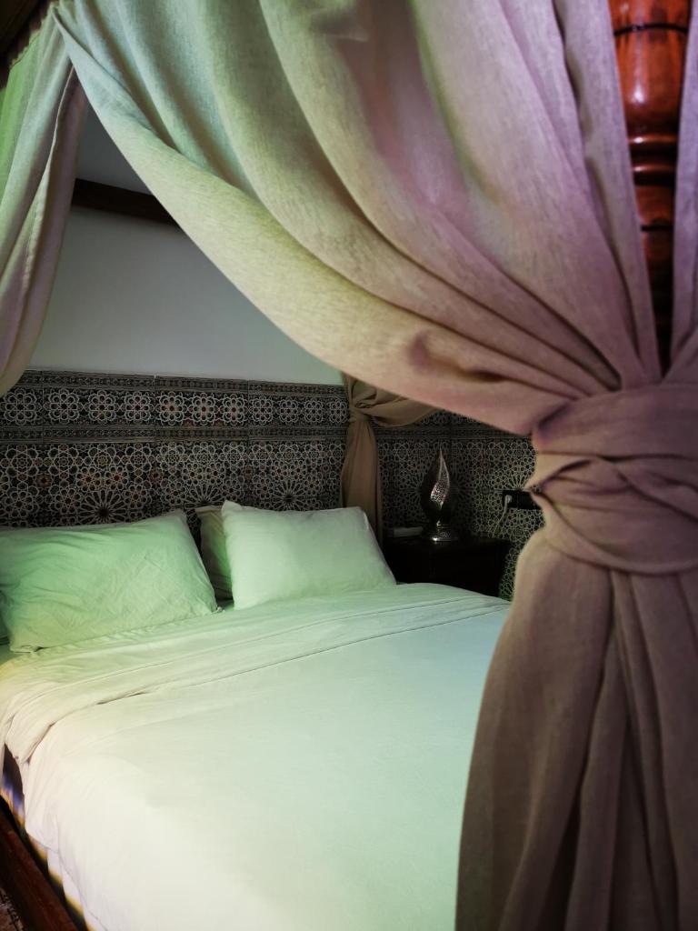 - une chambre avec un lit et un rideau au-dessus dans l'établissement Riad Dar Al Fassia, à Oujda