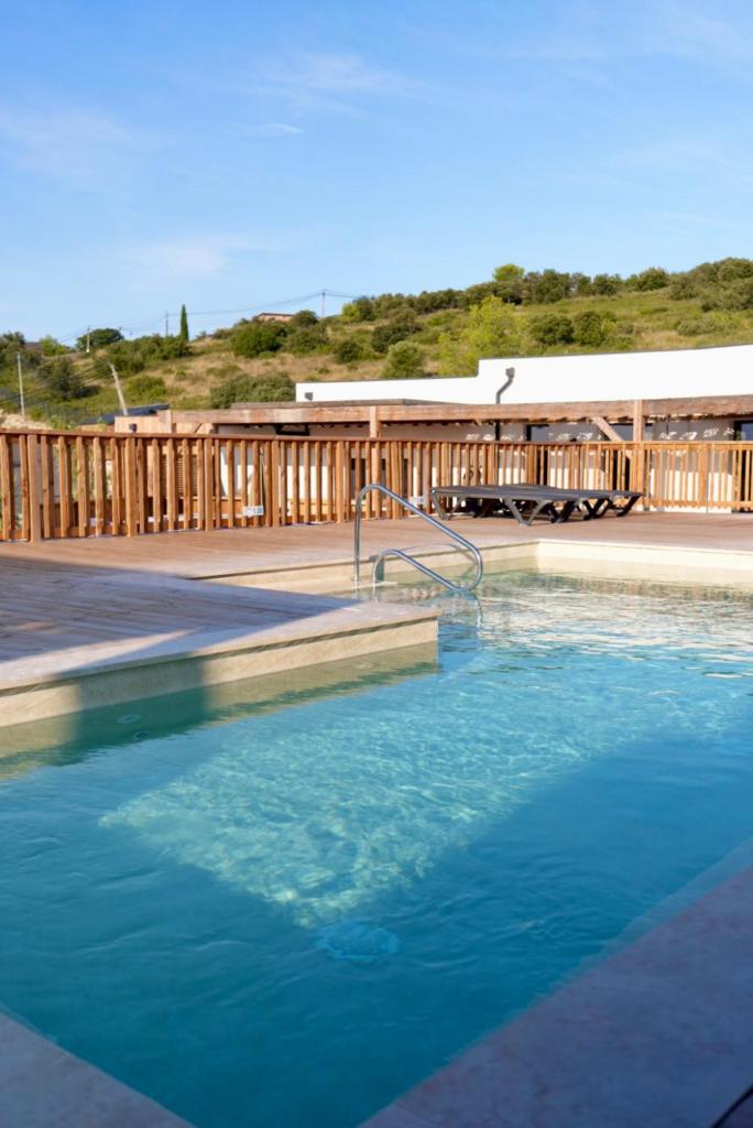 une grande piscine d'eau bleue devant un bâtiment dans l'établissement Camping les lodges du lagon, à Calvisson