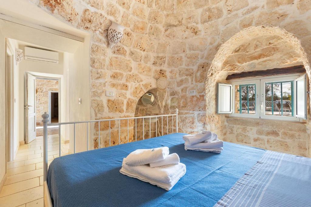 - une chambre avec un lit bleu dans un mur en pierre dans l'établissement Trullo Isabell by Perle di Puglia, à San Vito dei Normanni