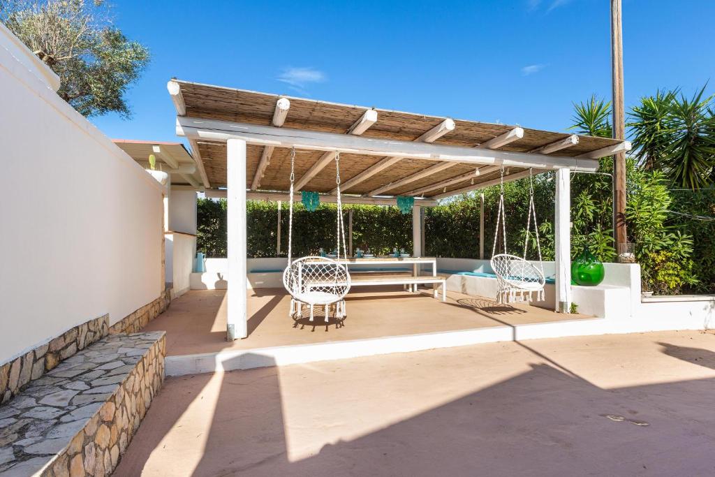 une pergola avec deux chaises et un banc sur une terrasse dans l'établissement Trullo Isabell by Perle di Puglia, à San Vito dei Normanni