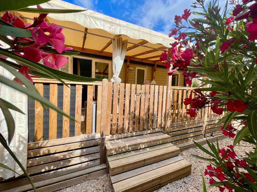 une maison avec une clôture en bois et quelques fleurs dans l'établissement Mobil-Home Les Lauriers Roses Camping Siblu 4****, à Fréjus