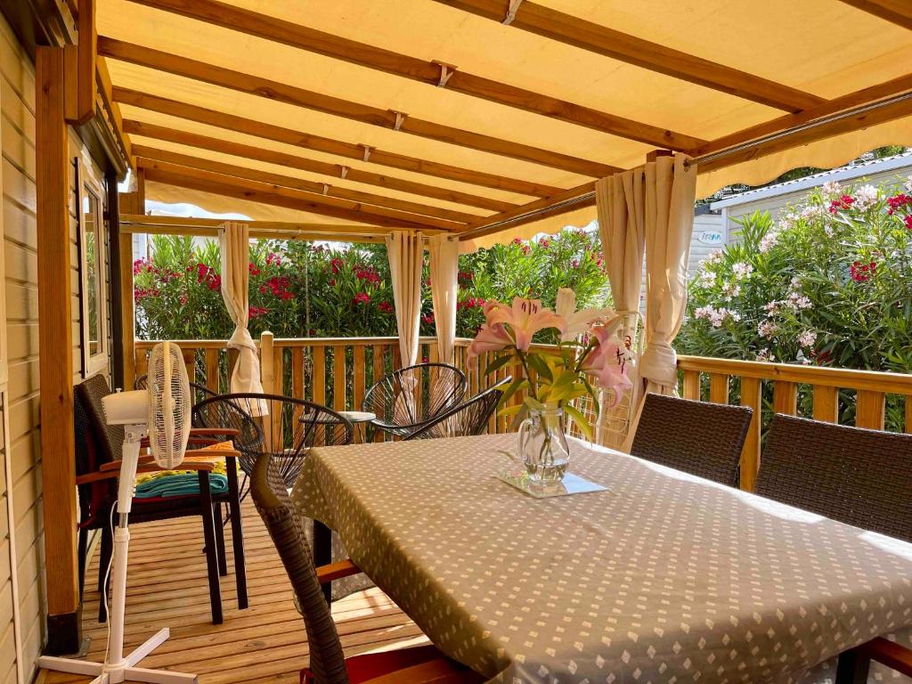 - une terrasse couverte avec une table et des chaises dans l'établissement Mobil-Home Les Lauriers Roses Camping Siblu 4****, à Fréjus