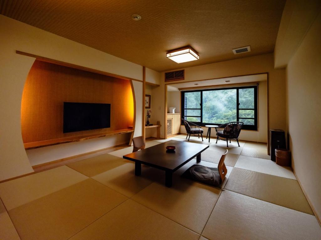 un salon avec une table et une télévision dans l'établissement Hotel Kazurabashi, à Miyoshi