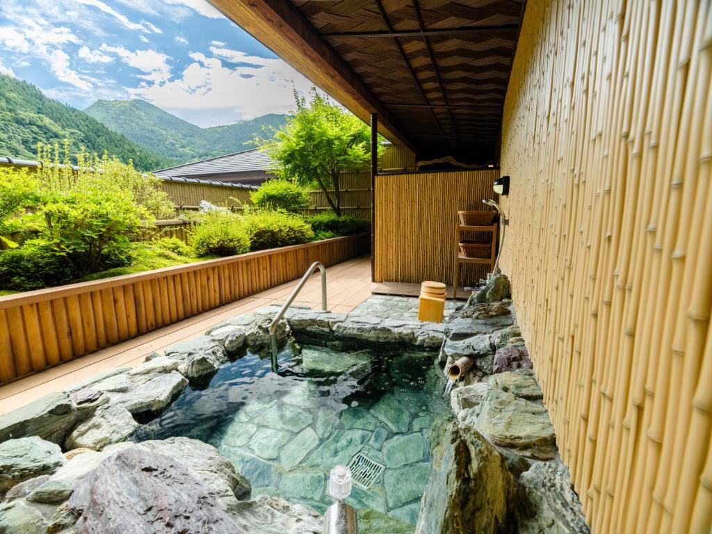 un bain à remous dans une arrière-cour avec un mur en pierre dans l'établissement Hotel Kazurabashi, à Miyoshi