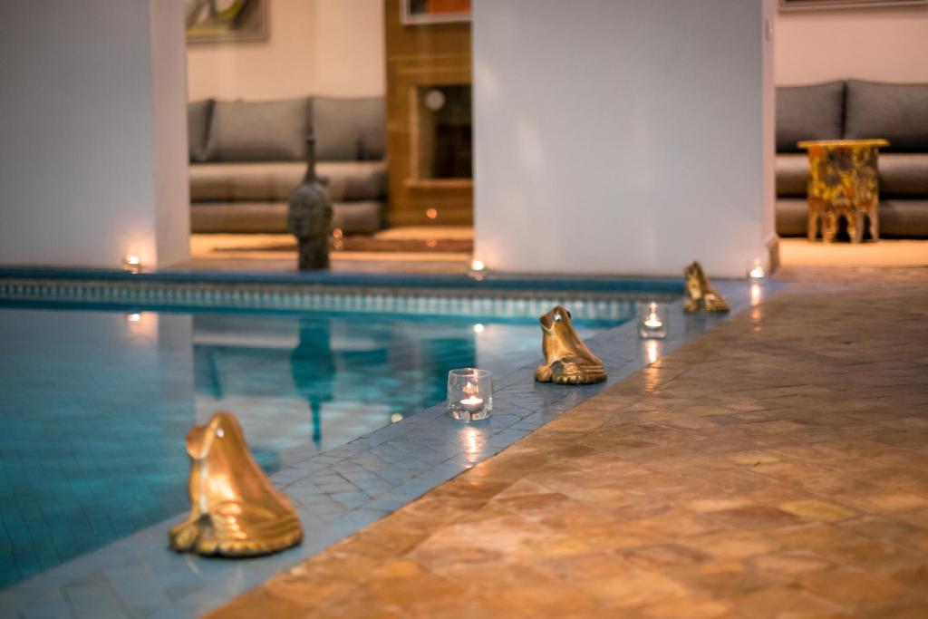 - une piscine avec des chaussures en or et un verre dans l'établissement Riad Zyo, à Rabat