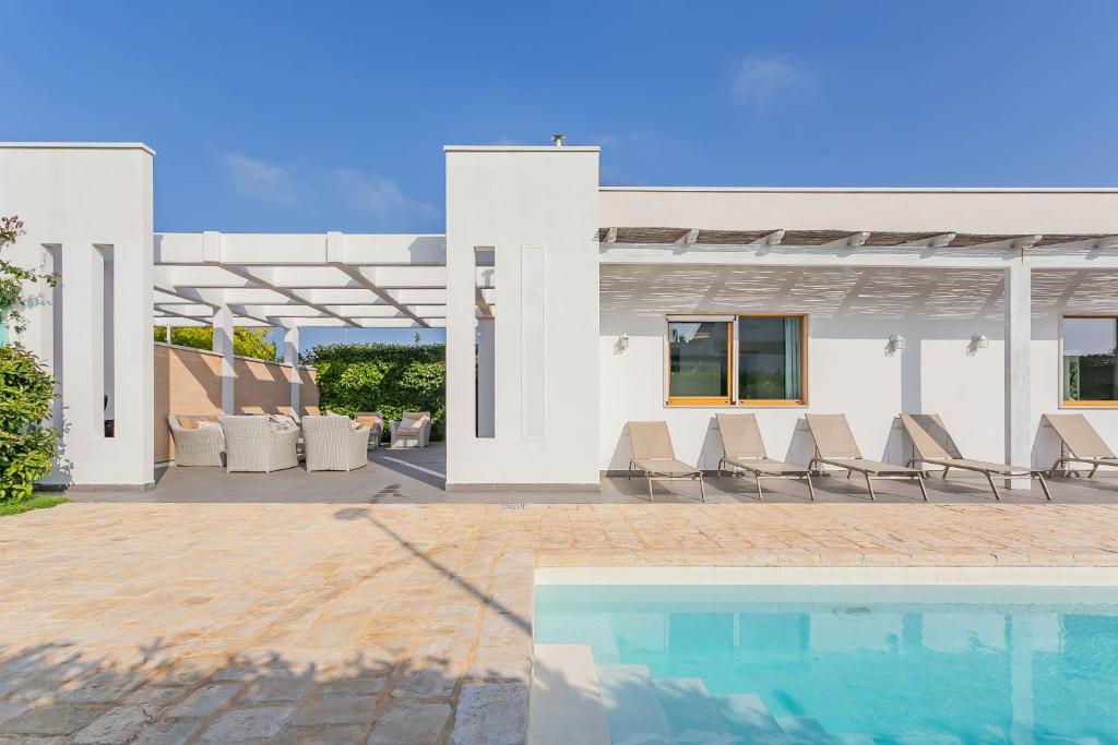 une maison blanche avec une piscine et des chaises dans l'établissement Villa Incanto nel Blu by Wonderful Italy, à Polignano a Mare