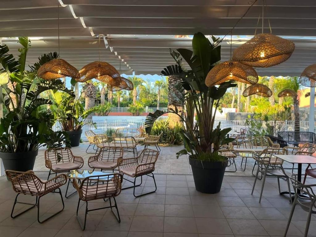 un restaurant avec des tables, des chaises et des plantes en pot dans l'établissement Grand MOBIL HOME Spatieux 40m2 - 2 Ch, à Argelès-sur-Mer