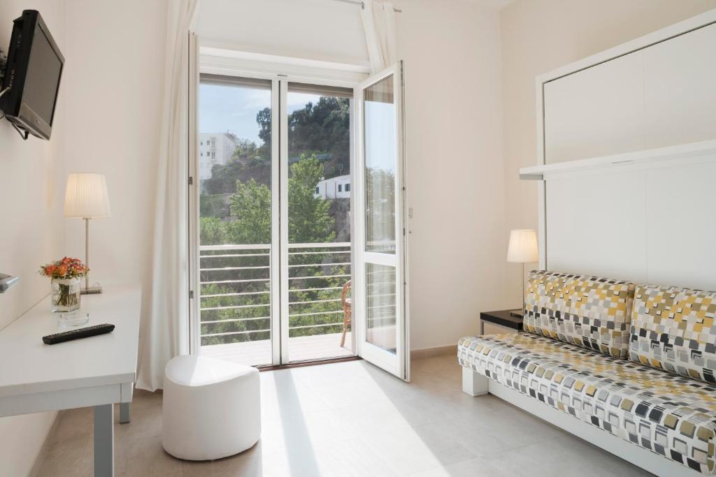 Cette chambre blanche dispose d'un canapé et d'une fenêtre. dans l'établissement Residence La Dolce Vita, à Maiori