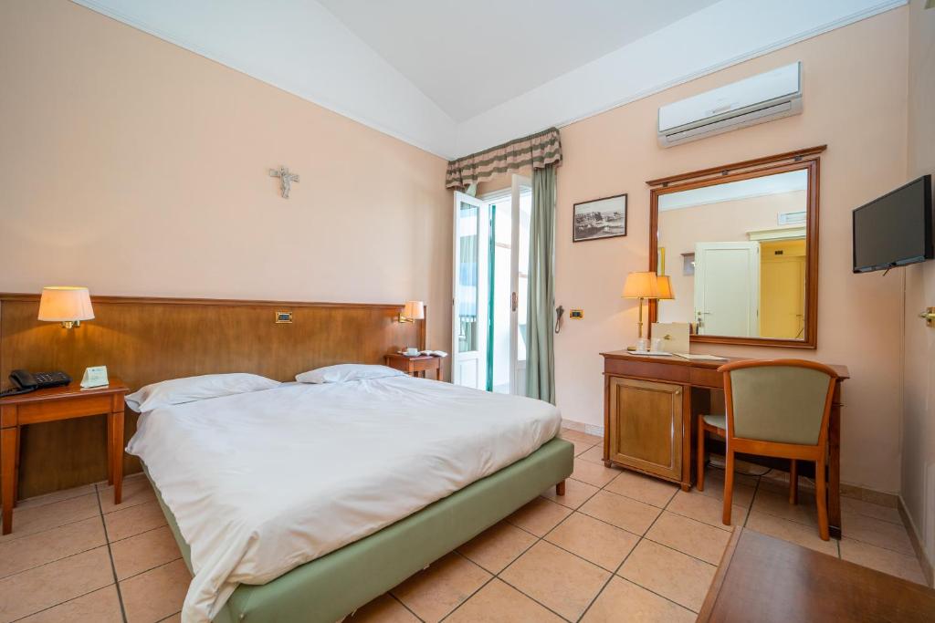 une chambre avec un lit, un bureau et un miroir dans l'établissement Hotel Santa Lucia, à Parghelia 92 autres photos