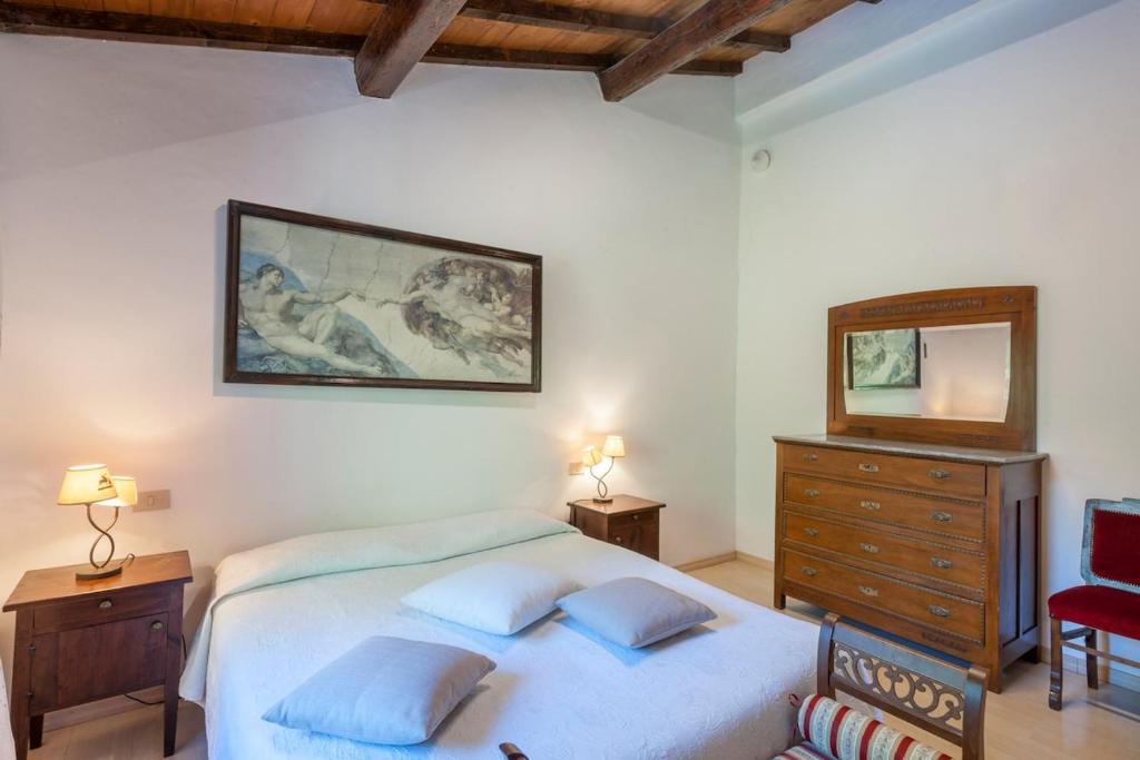 une chambre avec un lit, une commode et un miroir dans l'établissement Palazzo Ducale Urbino - Villa con Piscina, à Stazione delle Pole-Piobbico