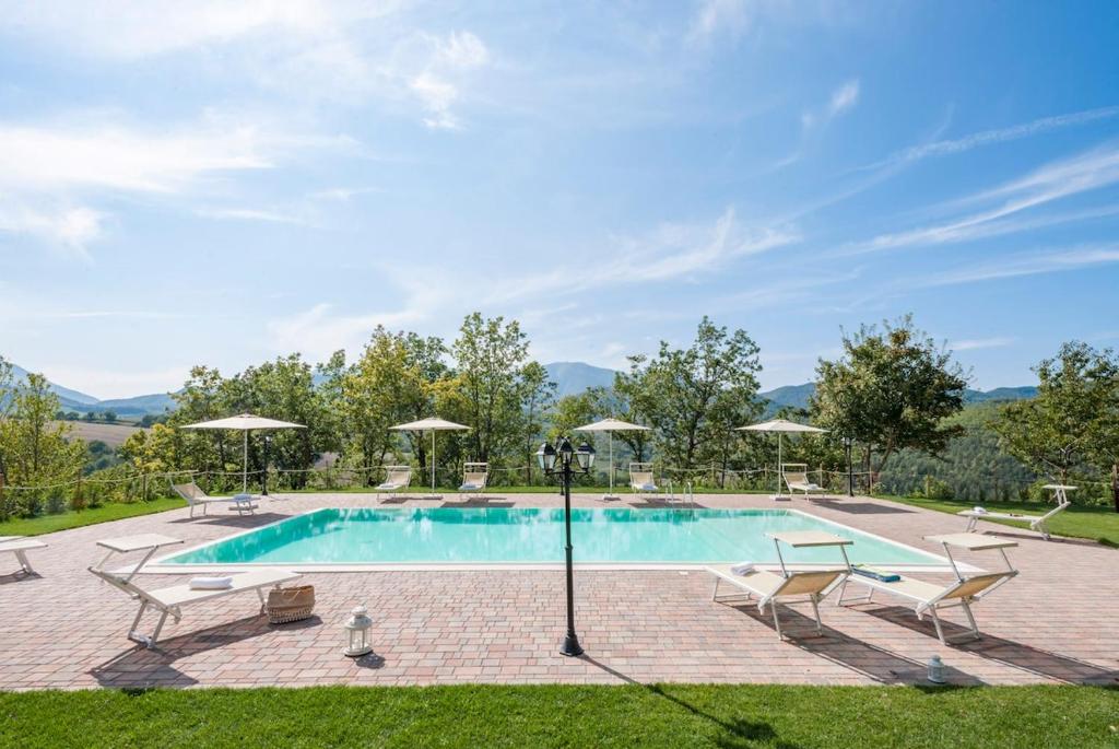 une piscine avec chaises et parasols dans une cour dans l'établissement Palazzo Ducale Urbino - Villa con Piscina, à Stazione delle Pole-Piobbico