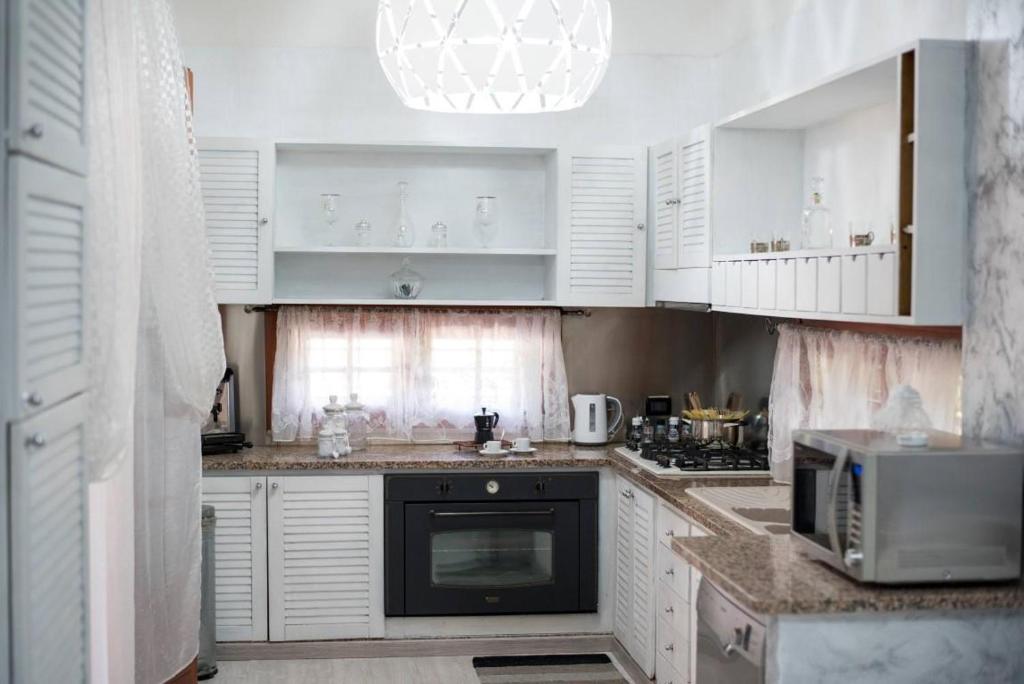 une cuisine avec des armoires blanches et un micro-ondes dans l'établissement Villa Aversa, à Castellammare del Golfo