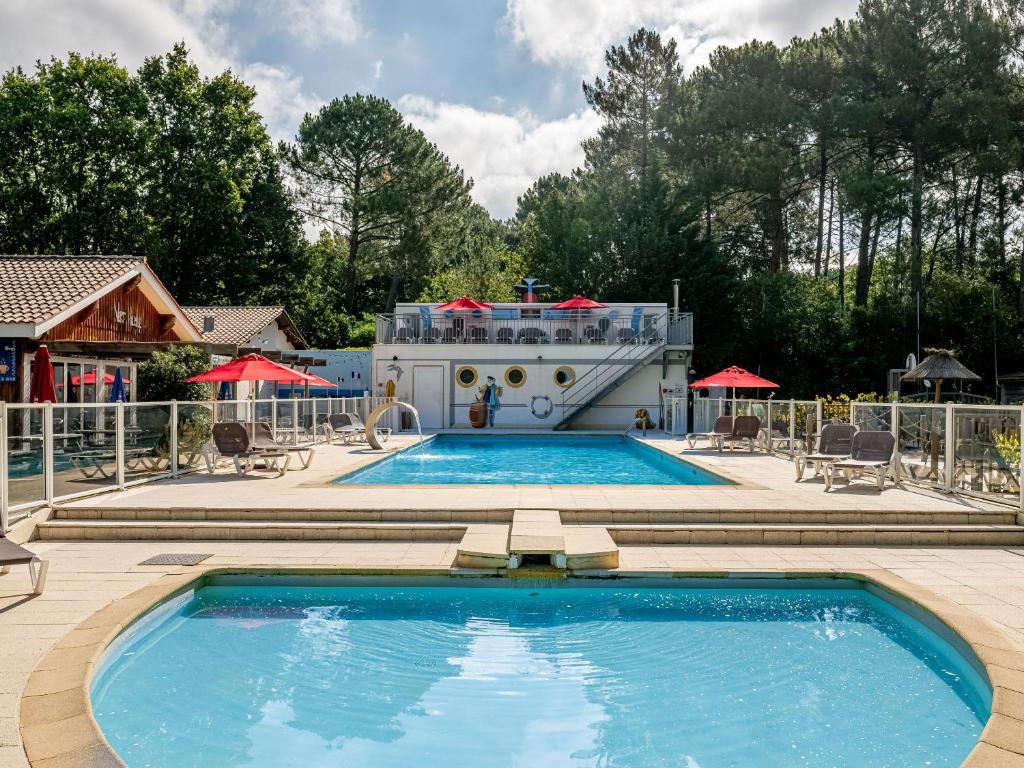 une grande piscine avec un bateau de croisière en arrière-plan dans l'établissement Domaine Résidentiel de Plein Air La Canadienne, à Arès
