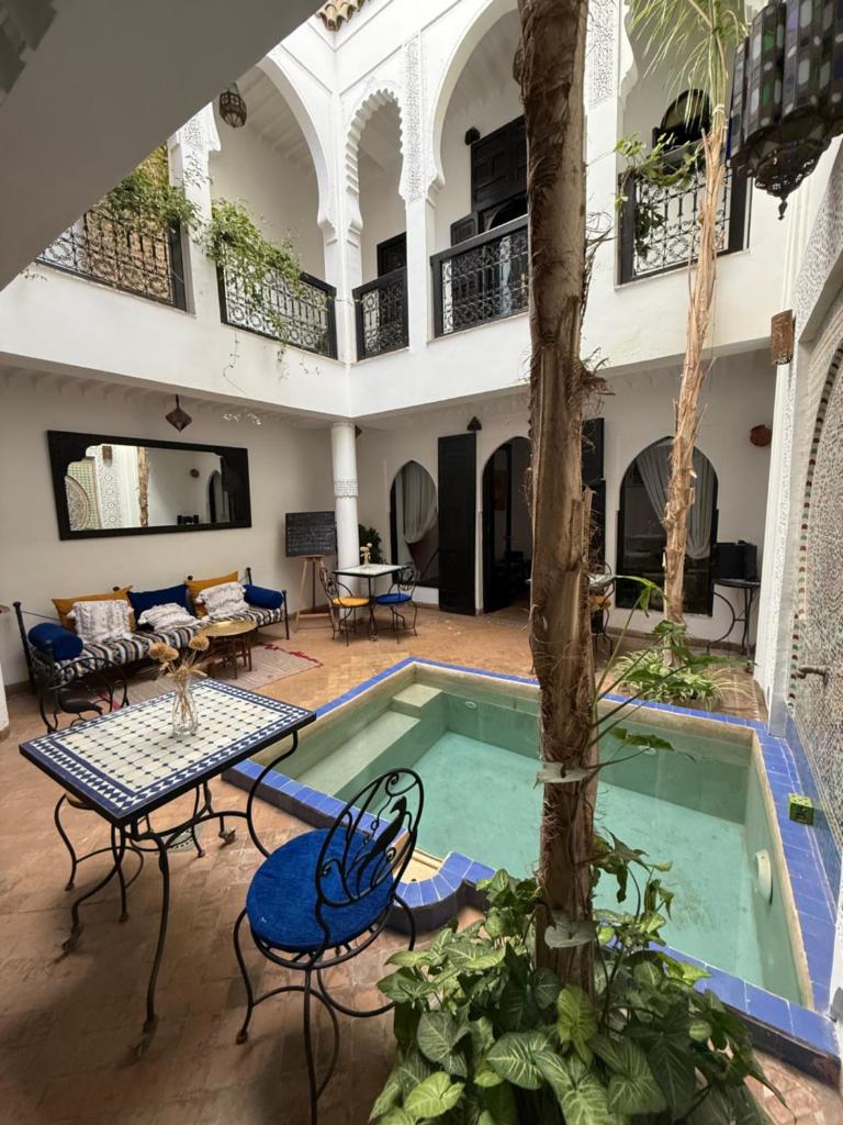 - une piscine intérieure avec une table et des chaises à côté d'un bâtiment dans l'établissement Dar Fangui, à Marrakech