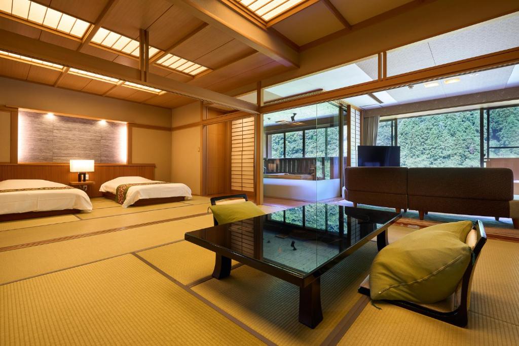 une chambre avec deux lits et une table dans une pièce dans l'établissement Shogawa Onsen Yumetsuzuri, à Tonami 33 autres photos