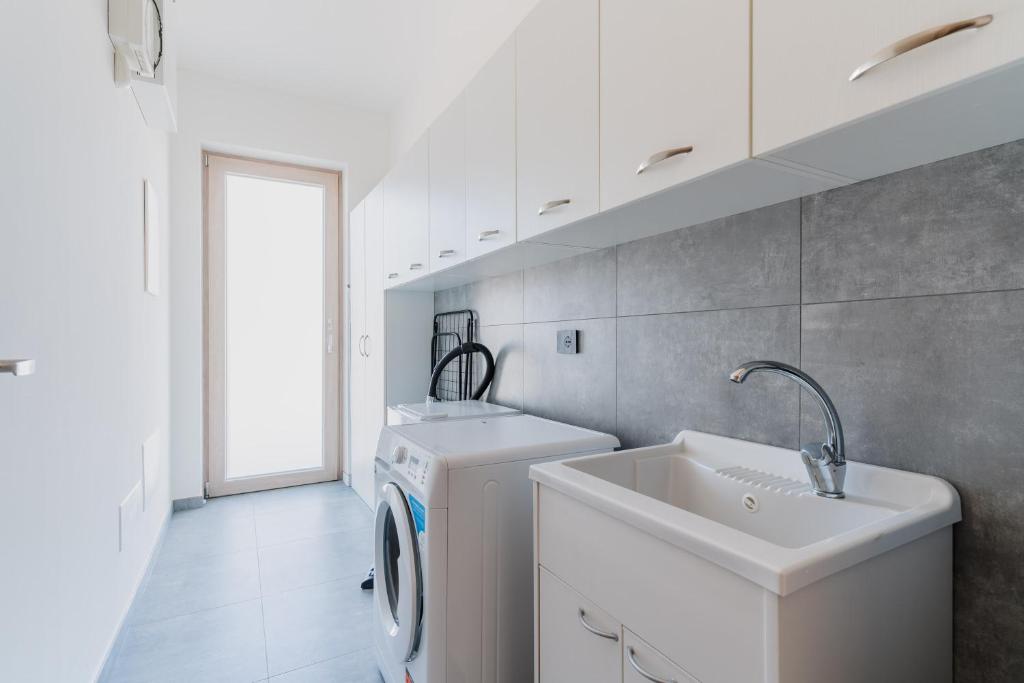 - une buanderie blanche avec un évier et un lave-linge dans l'établissement Villa Red Wind by Perle di Puglia, à Nardò
