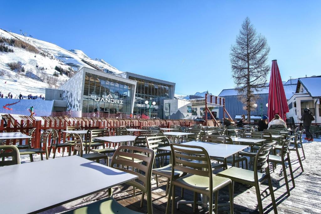 un groupe de tables et de chaises devant un bâtiment dans l'établissement Hôtel Les 2 Alpes L'Orée Des Pistes, à Les Deux Alpes