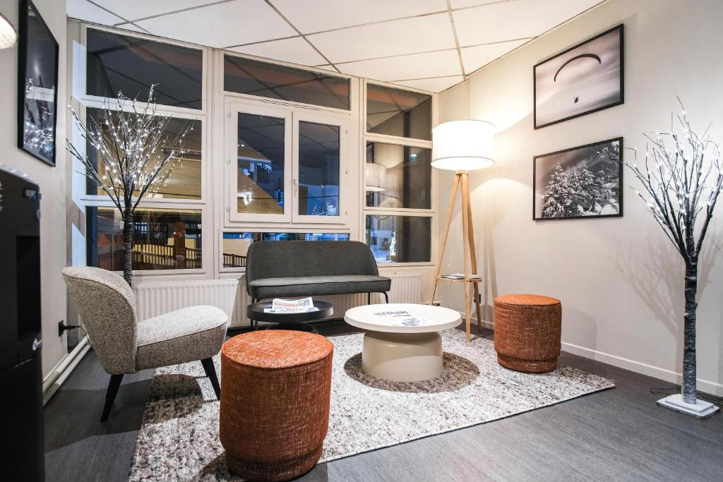 - un salon avec une chaise, un canapé et une table dans l'établissement Hôtel Les 2 Alpes L'Orée Des Pistes, à Les Deux Alpes