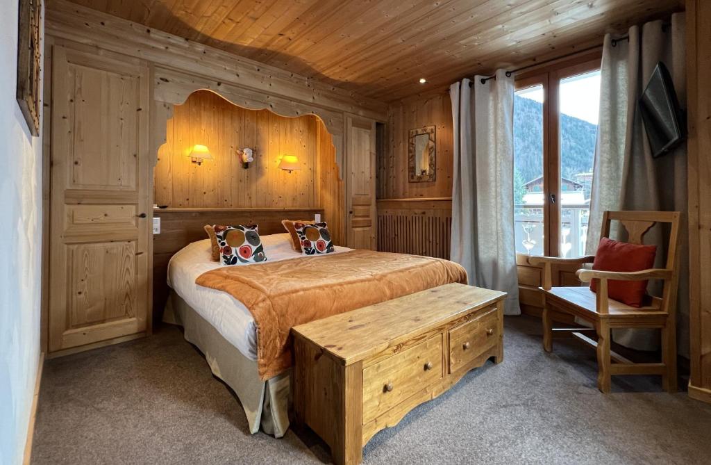 une chambre avec un lit et un plafond en bois dans l'établissement La Clef des Champs, à Morzine