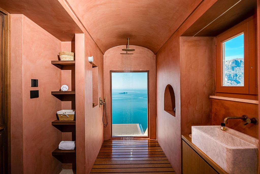 La salle de bains est pourvue d'un lavabo et offre une vue sur l'océan. dans l'établissement Antalia Boutique Hotel, à Positano