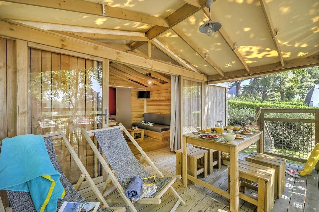 une chambre avec une table et des chaises sur une terrasse couverte dans l'établissement Domaine Résidentiel de Plein Air Le Conleau, à Vannes