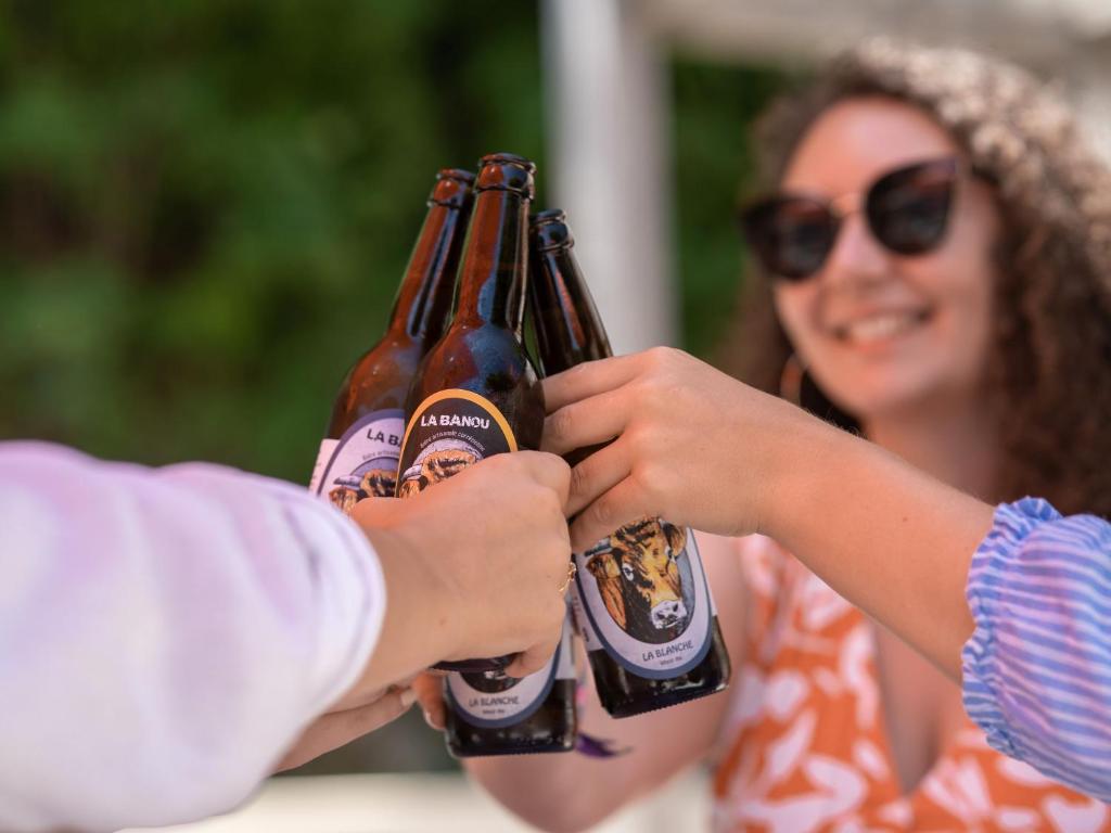 Deux personnes détiennent des bouteilles de bière dans l'établissement Domaine Résidentiel de Plein Air La Plage, à Treignac