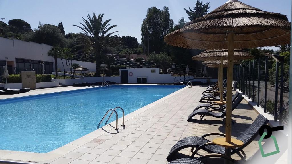 une piscine avec des chaises et un parasol à côté dans l'établissement Hotiday Apartments Cefalù, à Cefalù